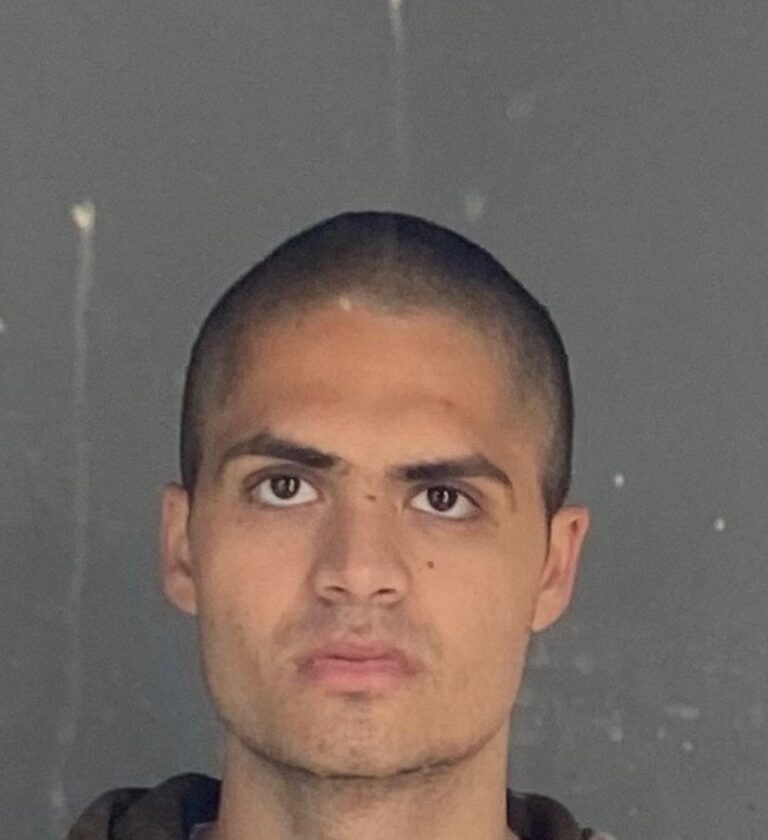 Shaved head young man with serious expression against a dark background - modern portrait.
